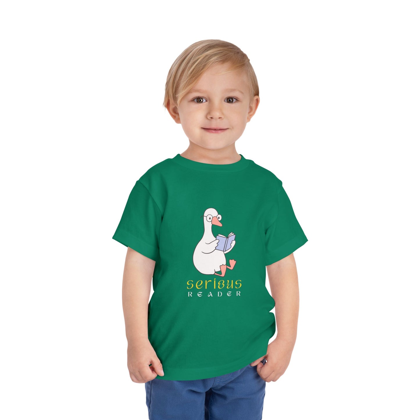 Toddler wearing a green t-shirt with a cartoon duck or goose reading a book and 'Serious Reader' text 
