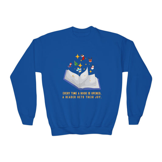 Blue sweatshirt with an open book graphic, Christmas images floating above it, text below 'Every time a book is opened, a reader gets their joy.'.