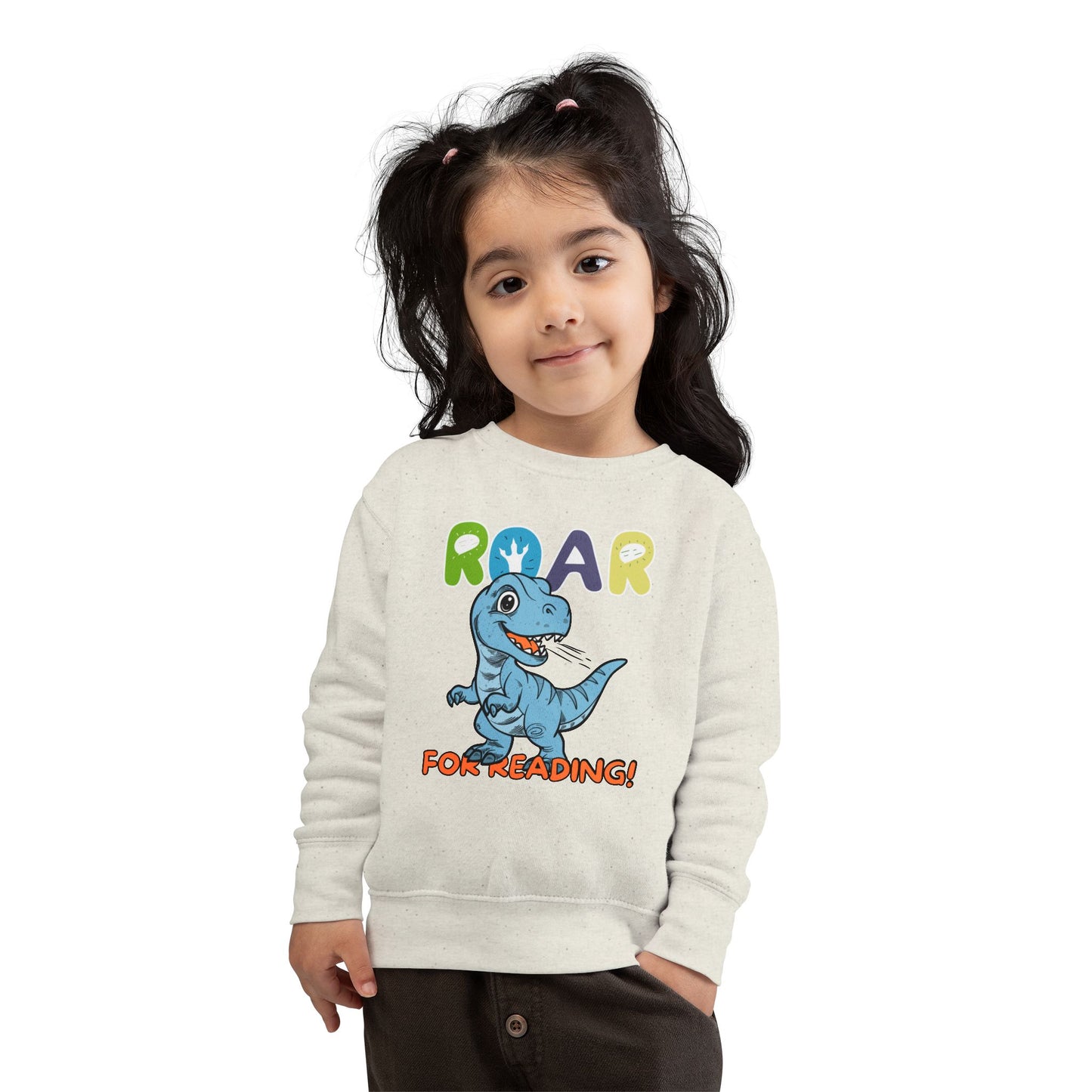 Girl wearing a beige toddler sweatshirt with a dinosaur graphic and 'Roar for Reading!' text 