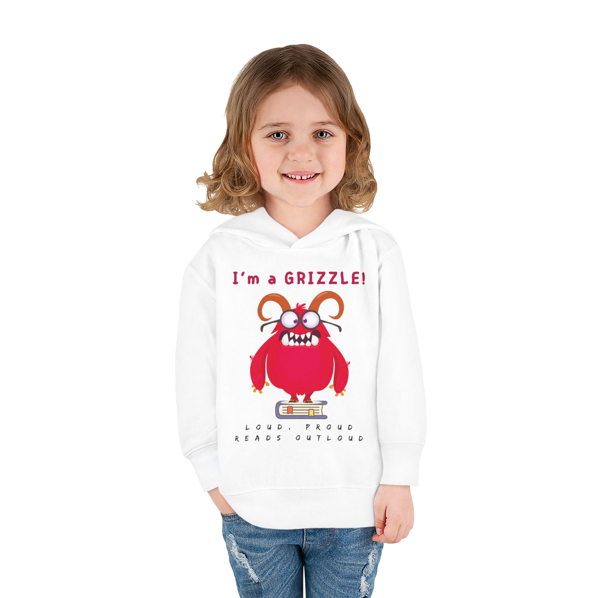 Girl wearing a white toddler hoodie with a red monster standing on a book and text' I'm a Grizzle'