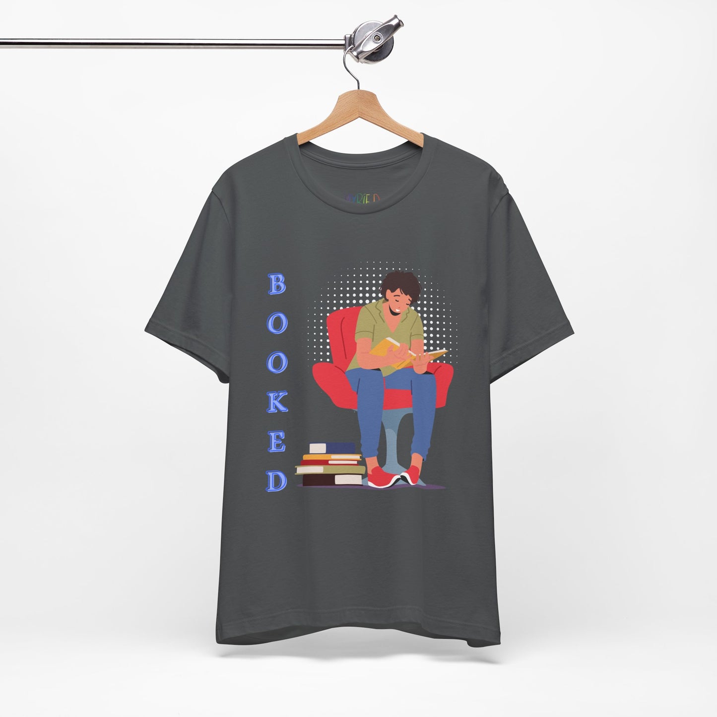 Gray t-shirt with a graphic of a person sitting in a chair, reading a book, a stack of books at his feet and text 'BOOKED' 