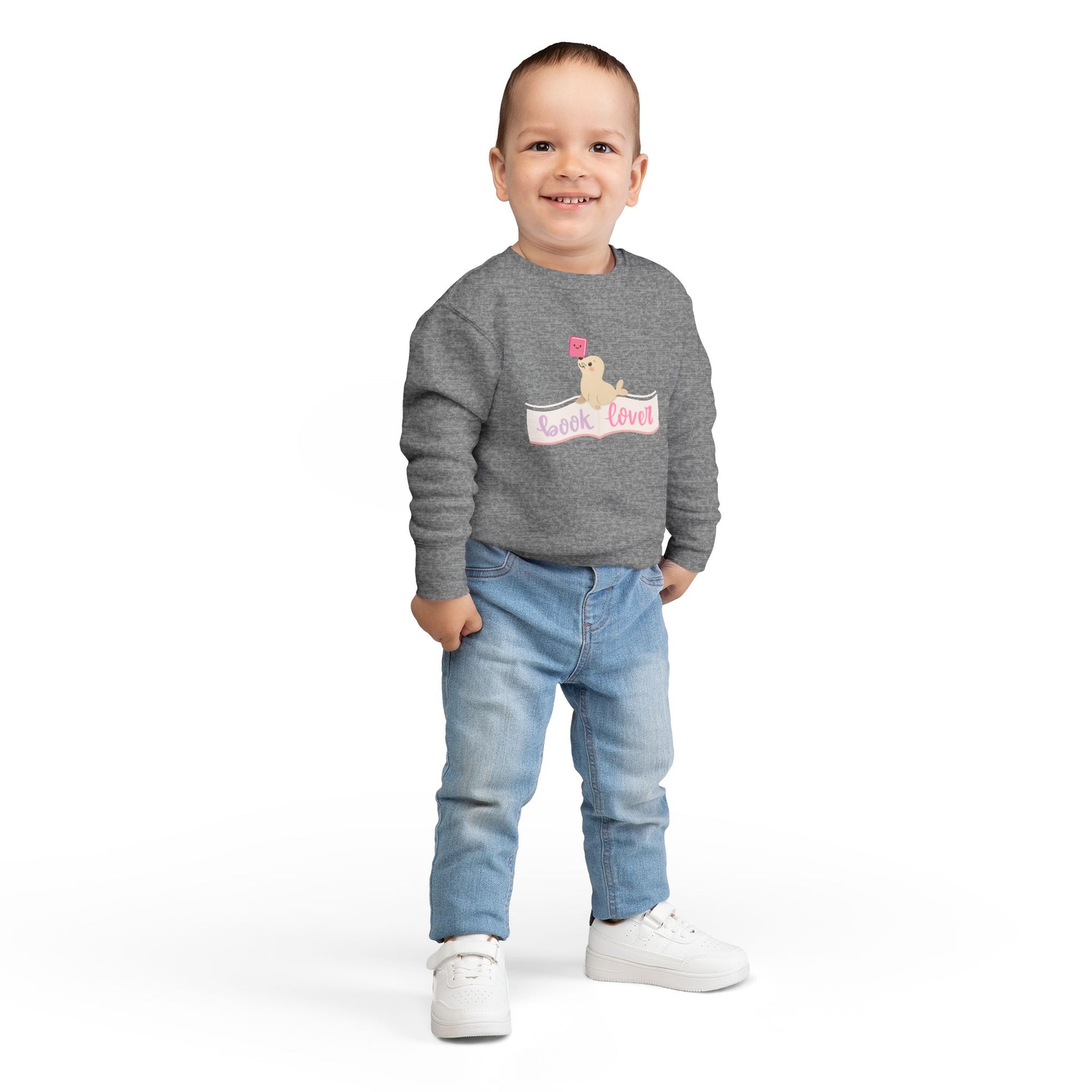 Boy wearing a gray toddler sweatshirt with a seal balancing a book on its nose and 'book lover' 