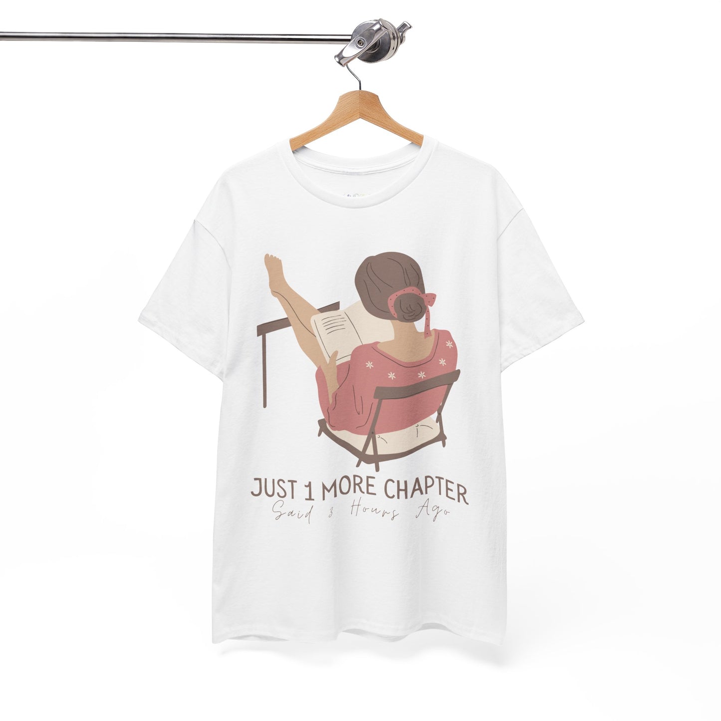 White t-shirt with a graphic of a person reading a book with her feet propped up and text 'Just 1 More Chapter, Read's Hours Ago' 
