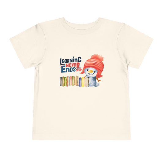 Beige toddler t-shirt with a snowman, a row of books and 'Learning Never Ends' text on a white background
