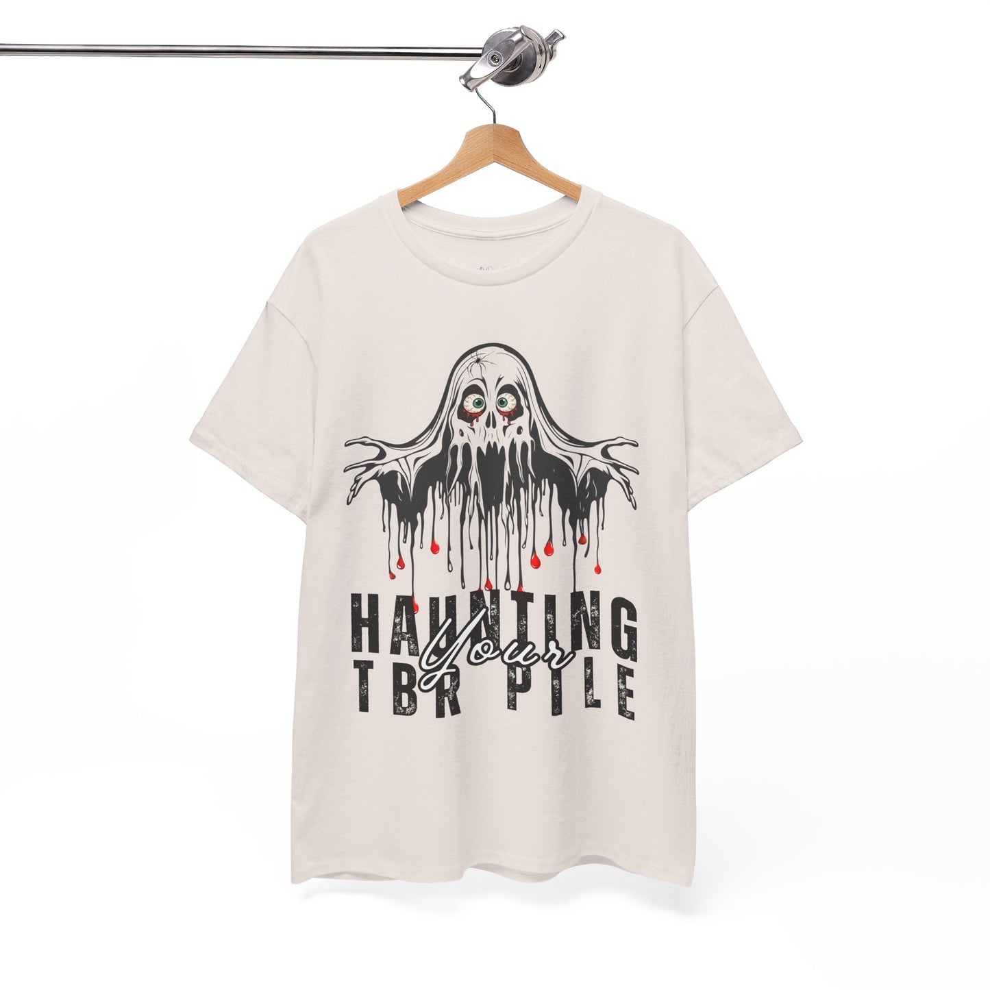 Beige t-shirt with ghost graphic and text 'Haunting Your TBR Pile' on a hanger against a white background