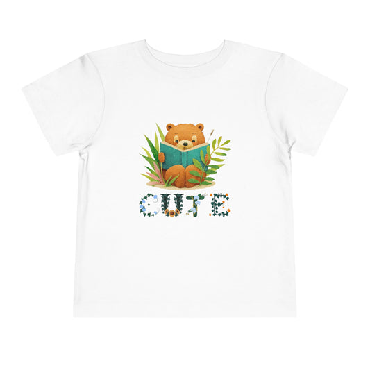 White t-shirt with a bear reading a book in tall grass and flowing text 'Cute' 