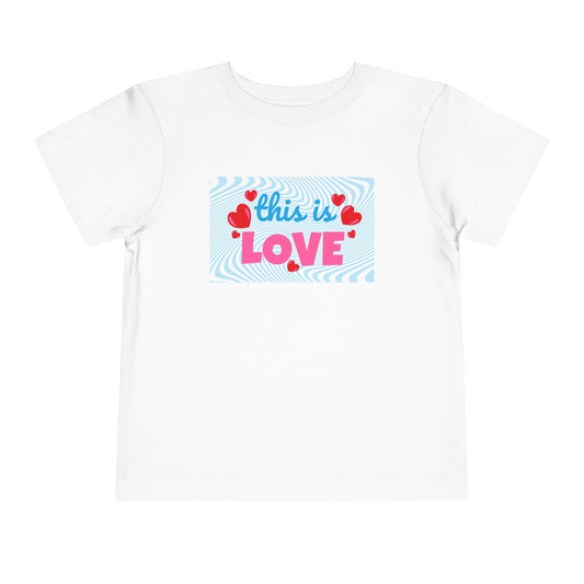 White t-shirt with 'this is LOVE' text and heart graphics on a swirling blue background