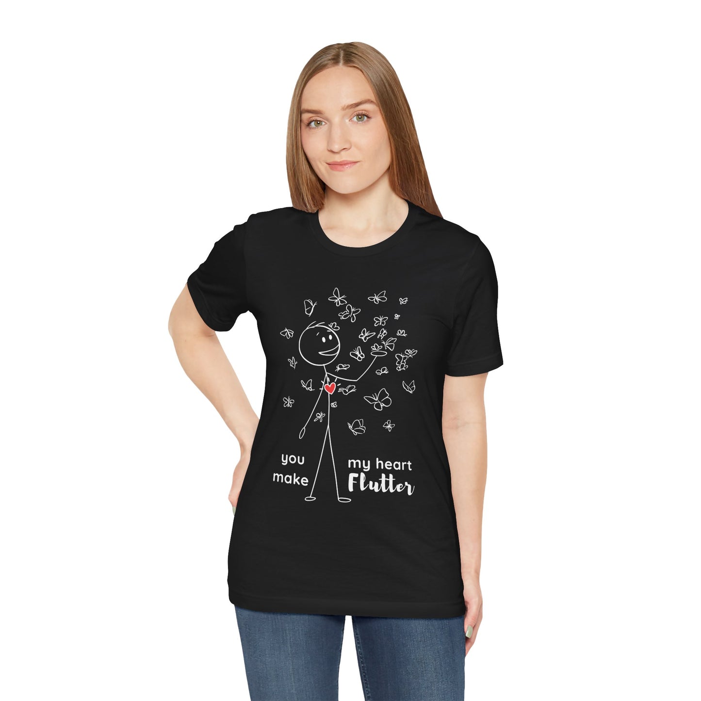 Woman wearing a black t-shirt with a stick figure surrounded by butterflies and a red heart beating on his chest, text 'You Make My Heart Flutter'