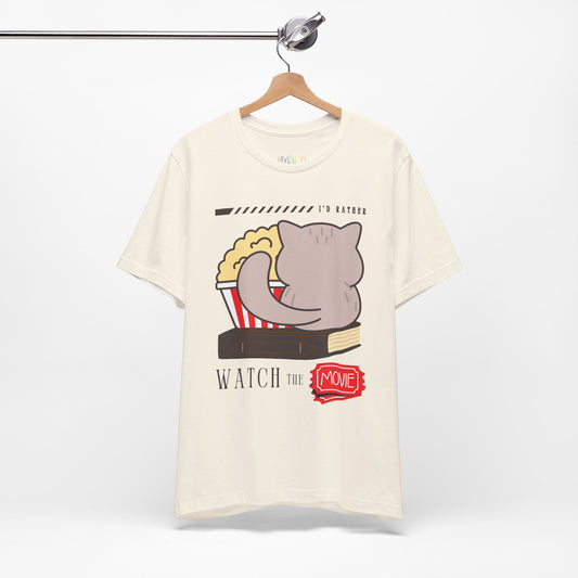 Beige t-shirt with the back of a cat, sitting on a book, with a bucket of popcorn, and text 'I'd Rather Watch The Movie' 