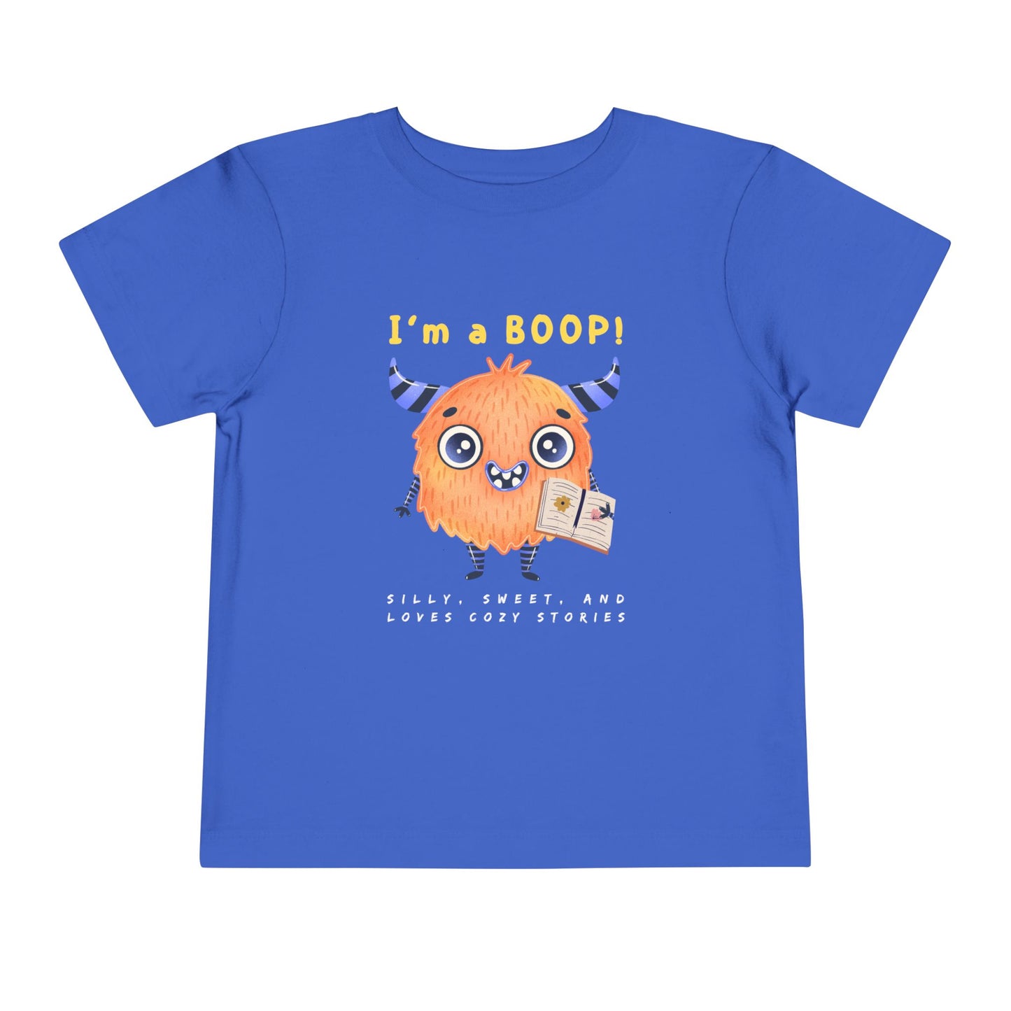 Blue toddler personality t-shirt with a cartoon monster holding a book, proudly proclaiming 'I'm A BOOP!' Sub-text "Silly, Sweet, And Loves Cozy Stories' on a white background