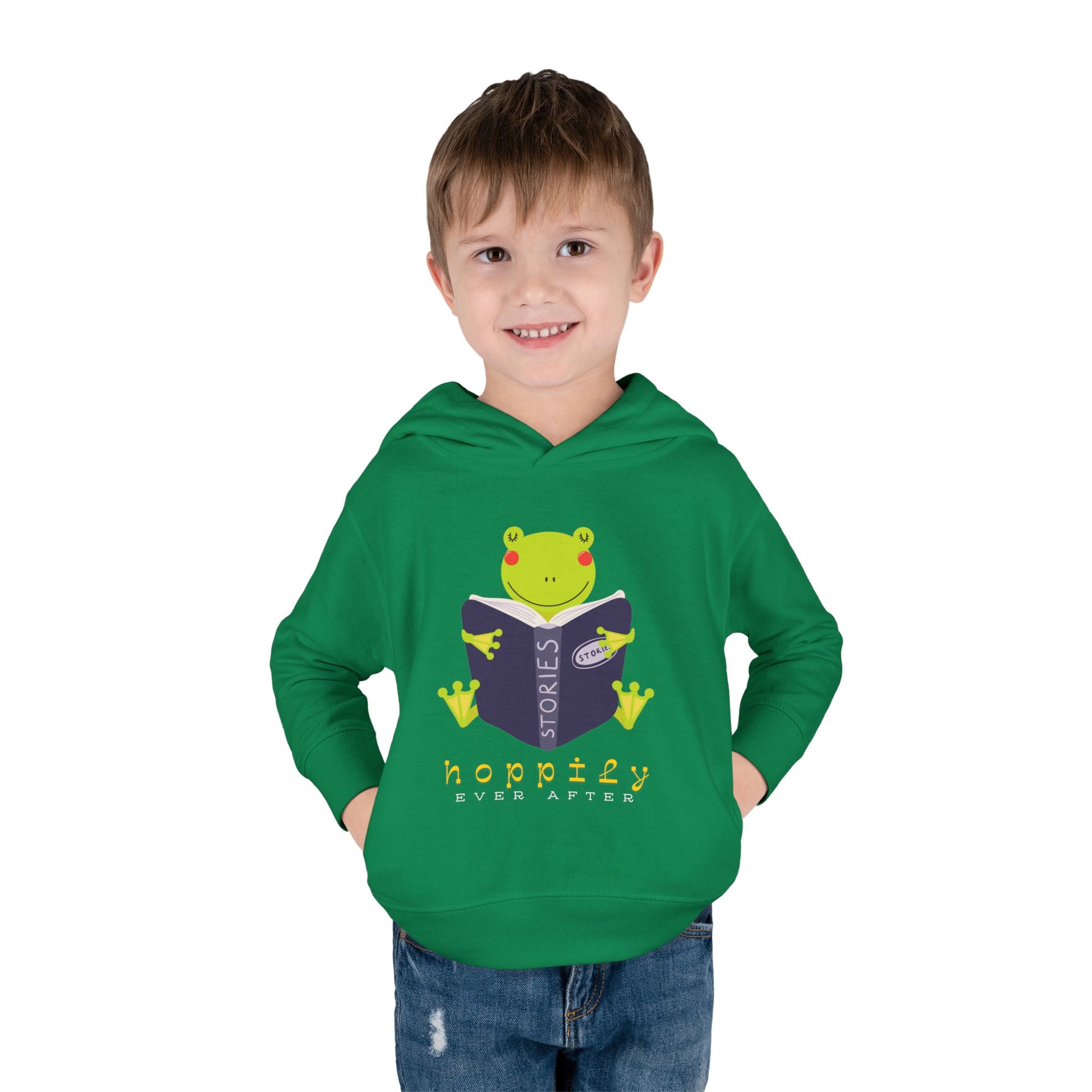 Boy wearing a green toddler hoodie with a frog hugging an open book and text 'hoppily ever after'