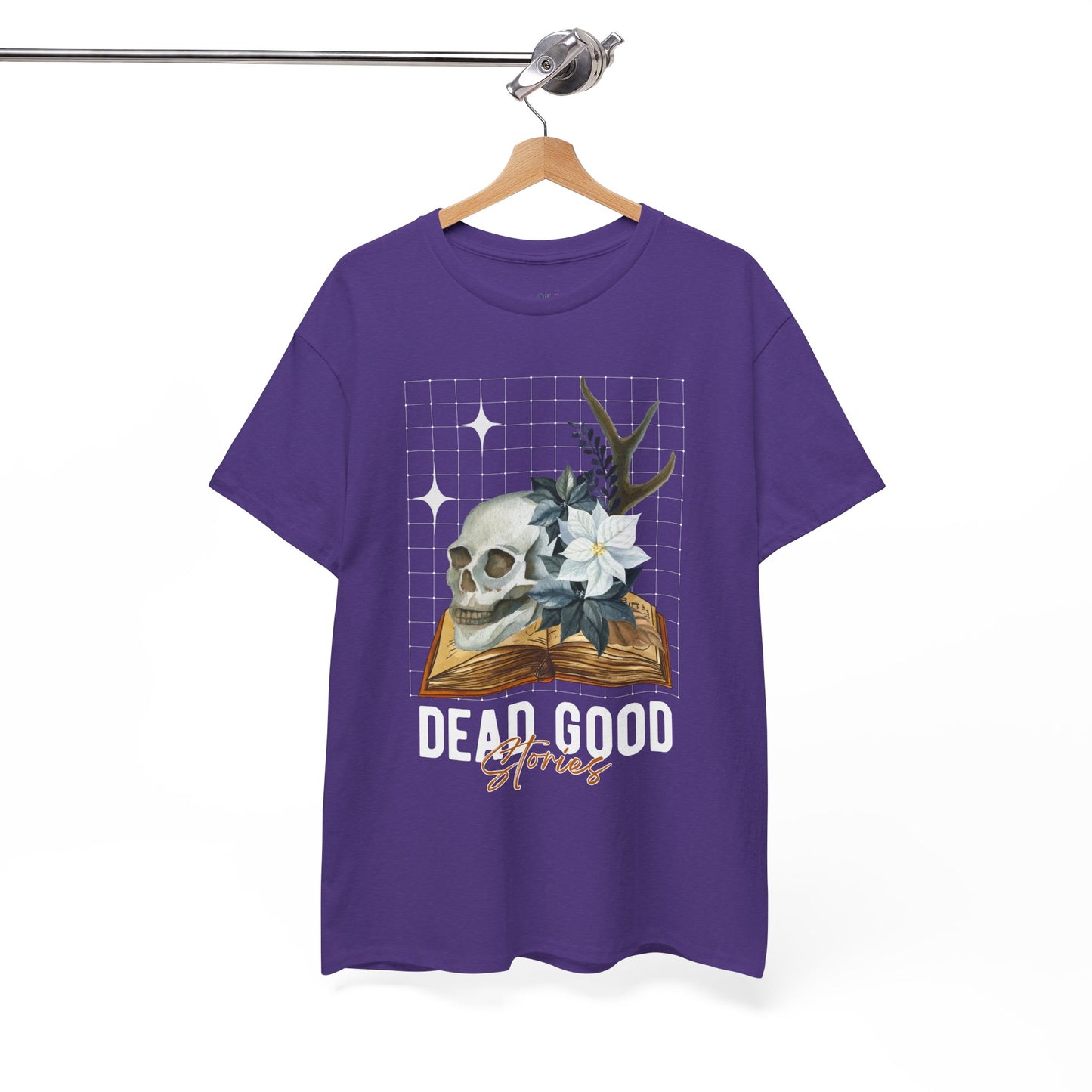 Purple t-shirt with skull, antler, and flower on a book with text 'Dead Good Stories' on a hanger against a white background