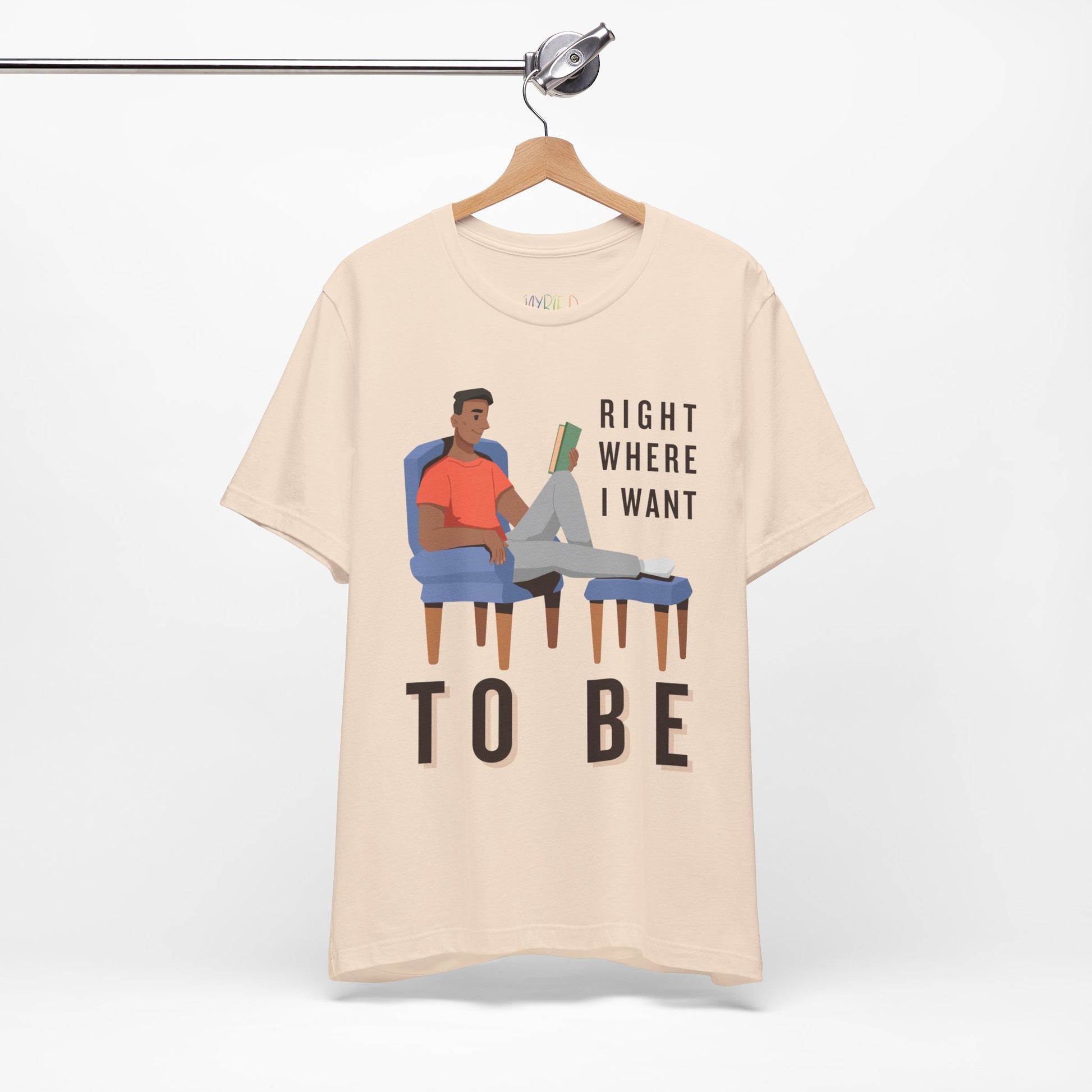 Beige t-shirt with a man lounging in a chair, feet up, book in hand and text 'Right Where I Want To Be'