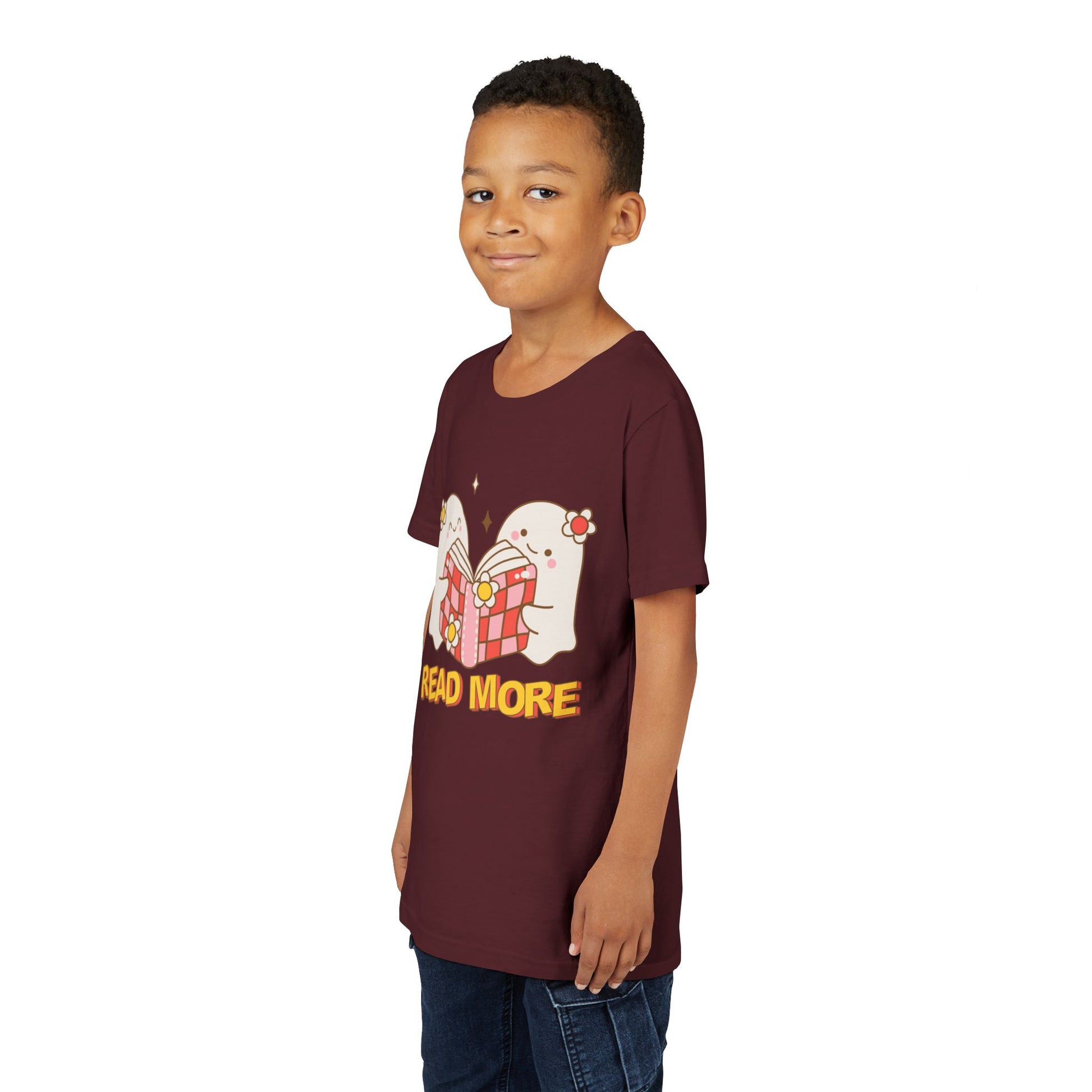 Child wearing a maroon t-shirt with cartoon ghosts reading a shared book and 'Read More' text 