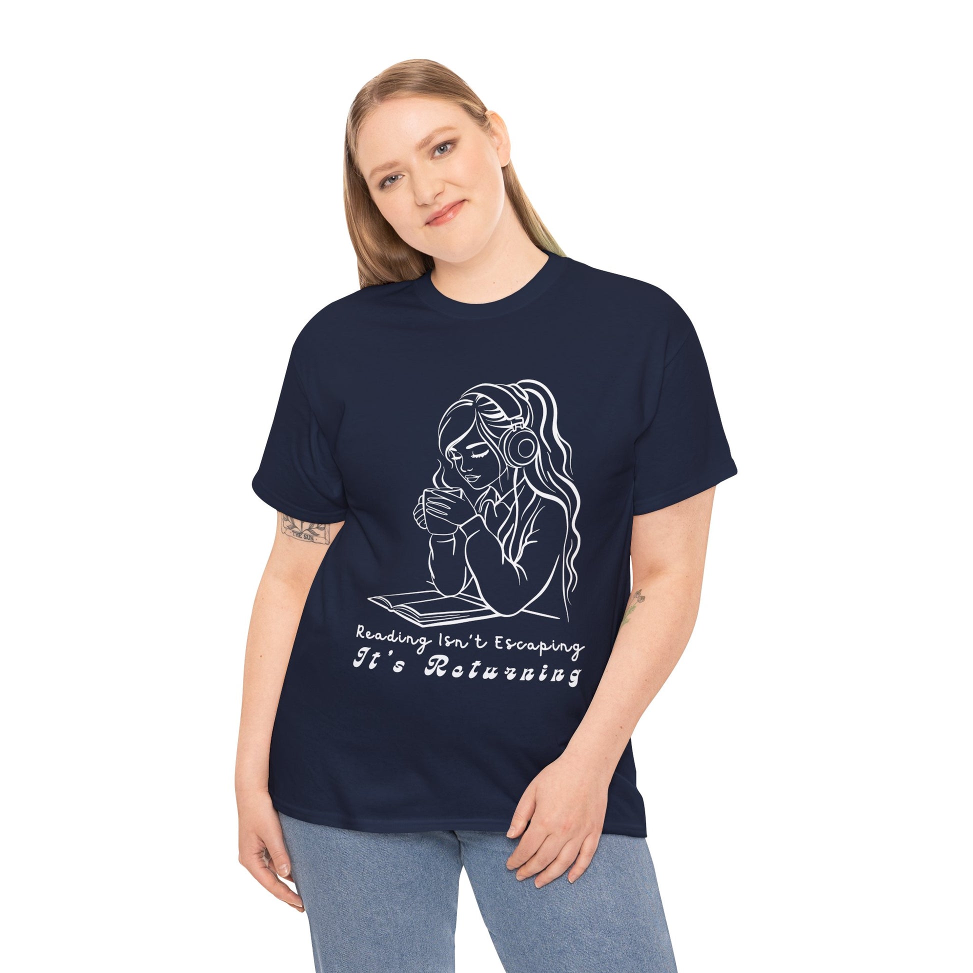 Woman wearing a navy blue t-shirt with a woman wearing headphones, cupping a hot beverage and reading a book, text 'Reading Isn't Escaping, It's Returning'
