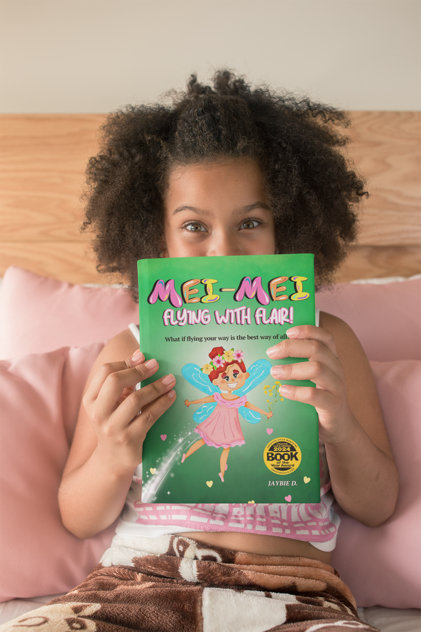 Child smiling while holding the Mei-Mei Flying With Flair picture book about confidence, individuality, and self-expression