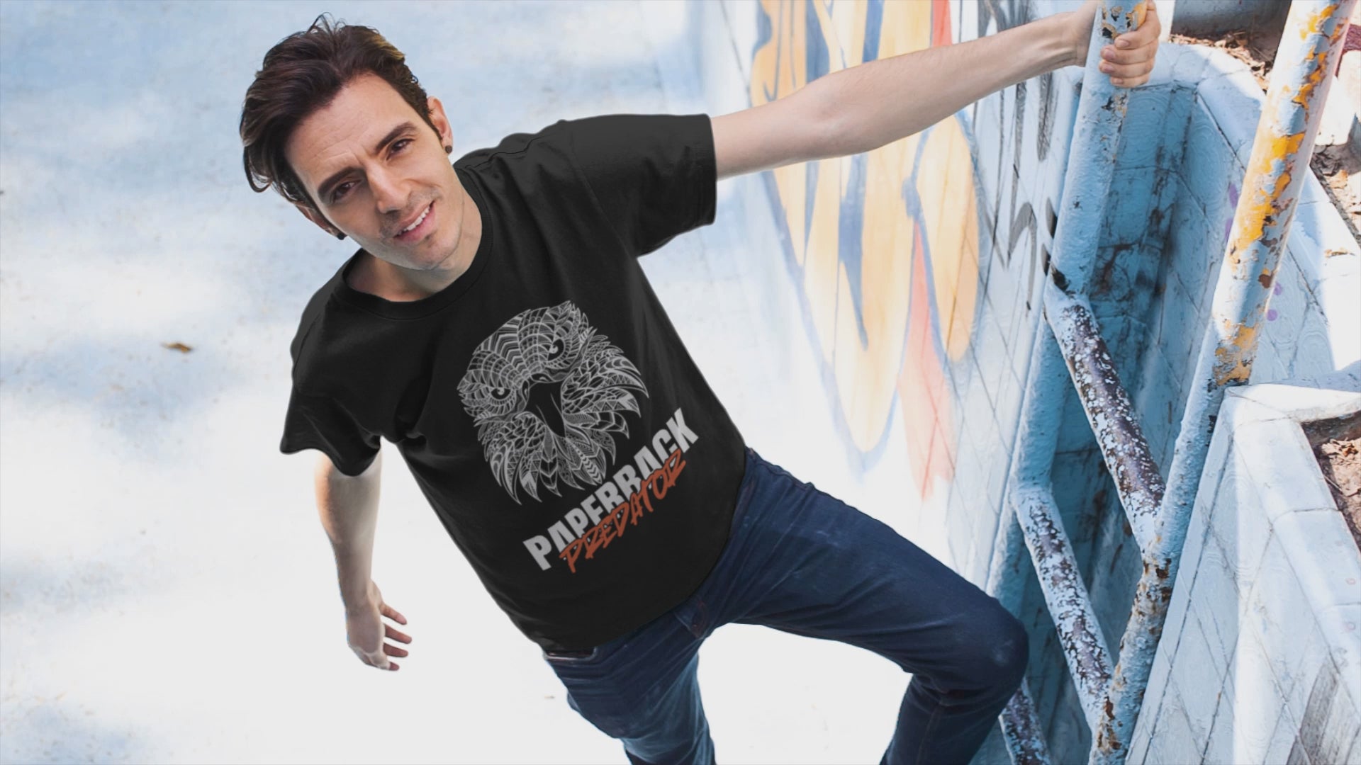 Load video: video of a man hanging off a pool ladder while modeling a black Paperback Predator t-shirt by Jaybie D.
