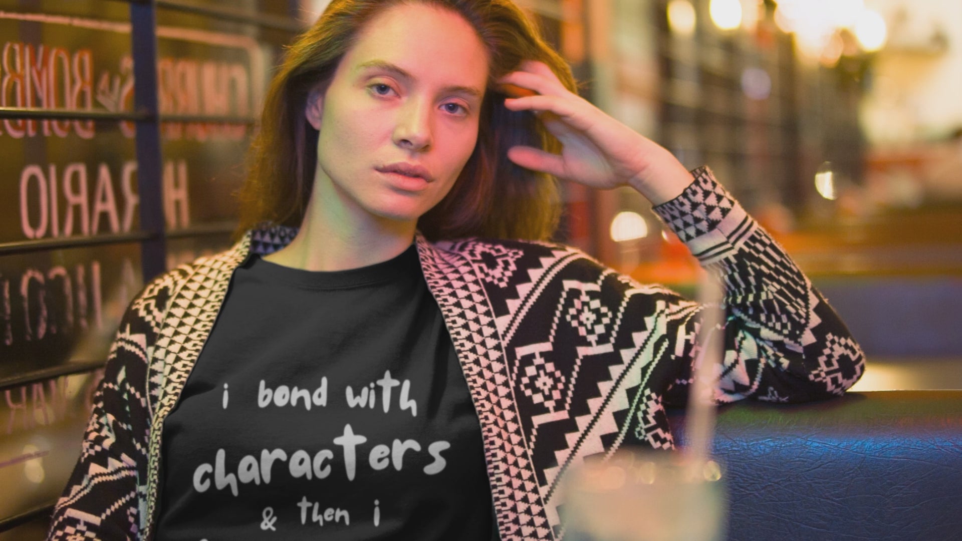 Load video: Video of a woman in front of a shop, wearing a black t-shirt with text &#39;I Bond With Characters And Then I Mourn&#39;, by Jaybie D.